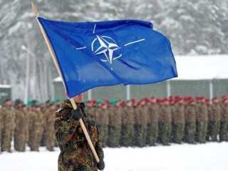 Bandeira da Otan é ostentada por militar (Foto: Reuters)